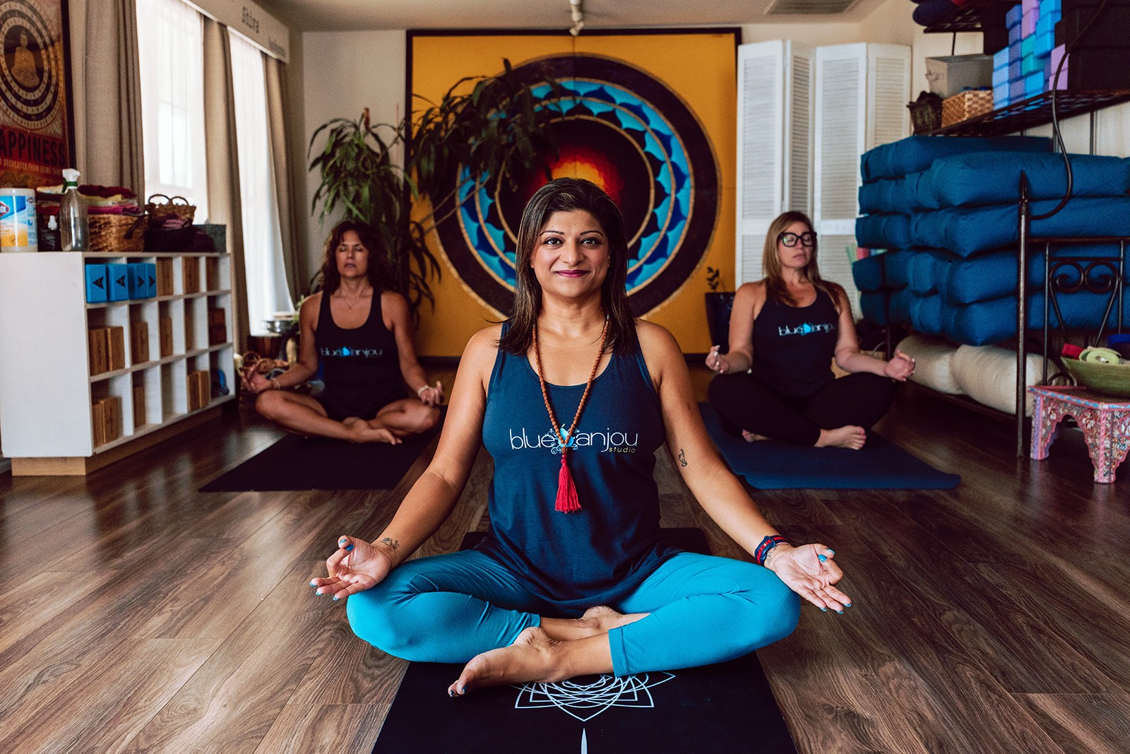 Noshin seated cross-legged in meditation in front of the studio mandala