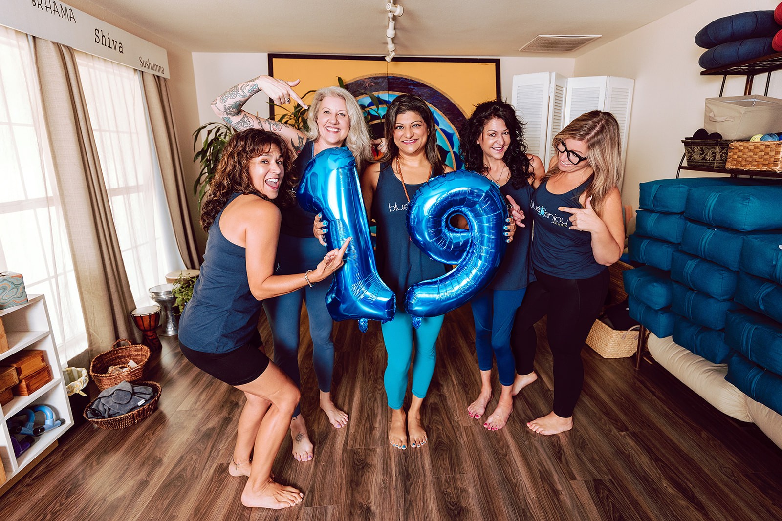Blue Anjou teachers gathered together with blue 19 balloons in the studio