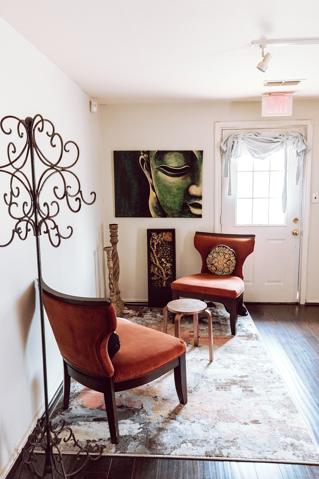 Two rust-colored chairs in the Reiki corner beneath a green Buddha painting
