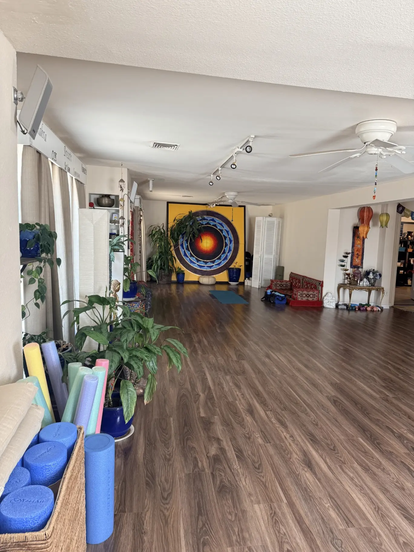 Open practice room with the blue and gold mandala painting and wood floors