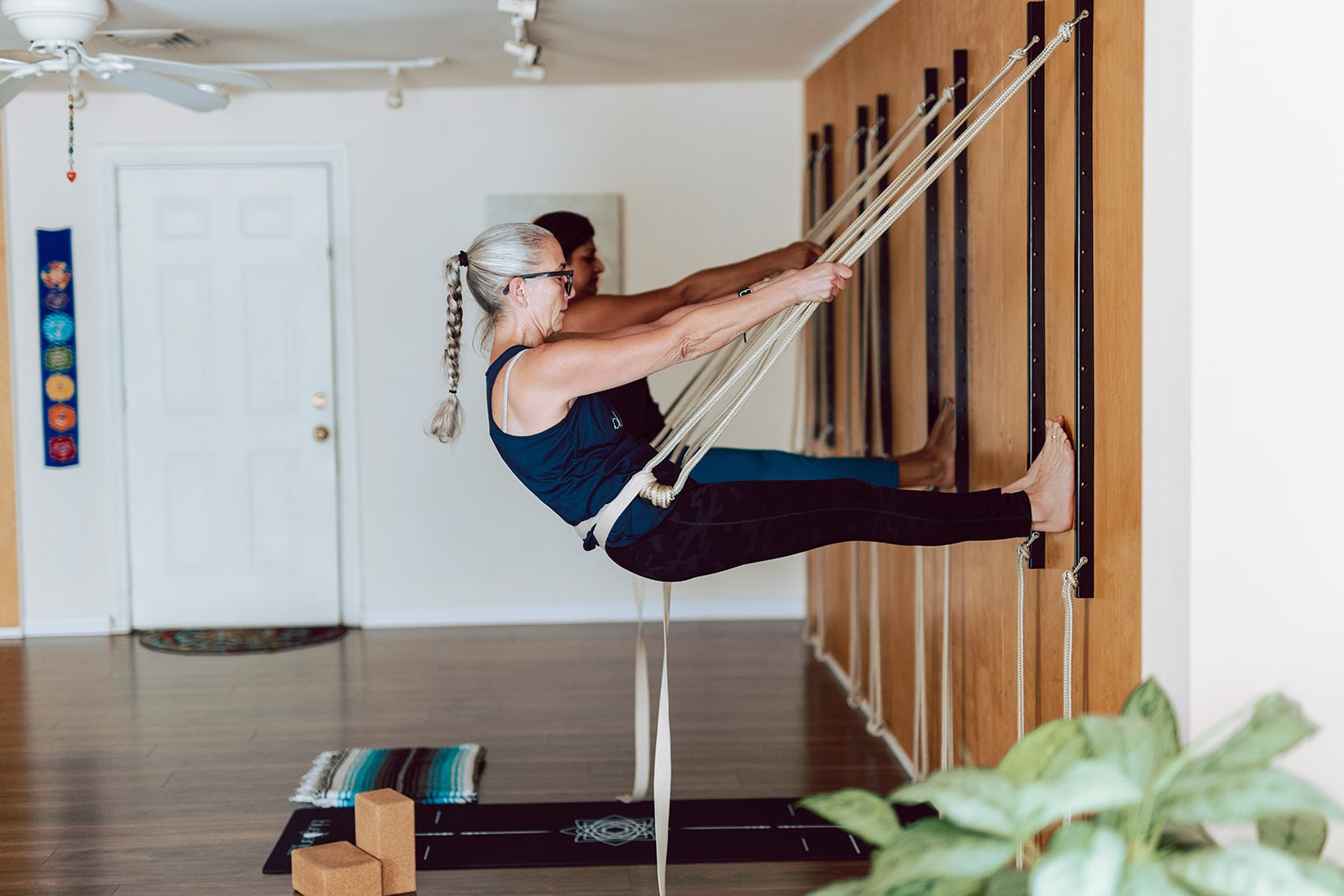 Student holding a suspended seated shape in the ropes with a teacher assisting