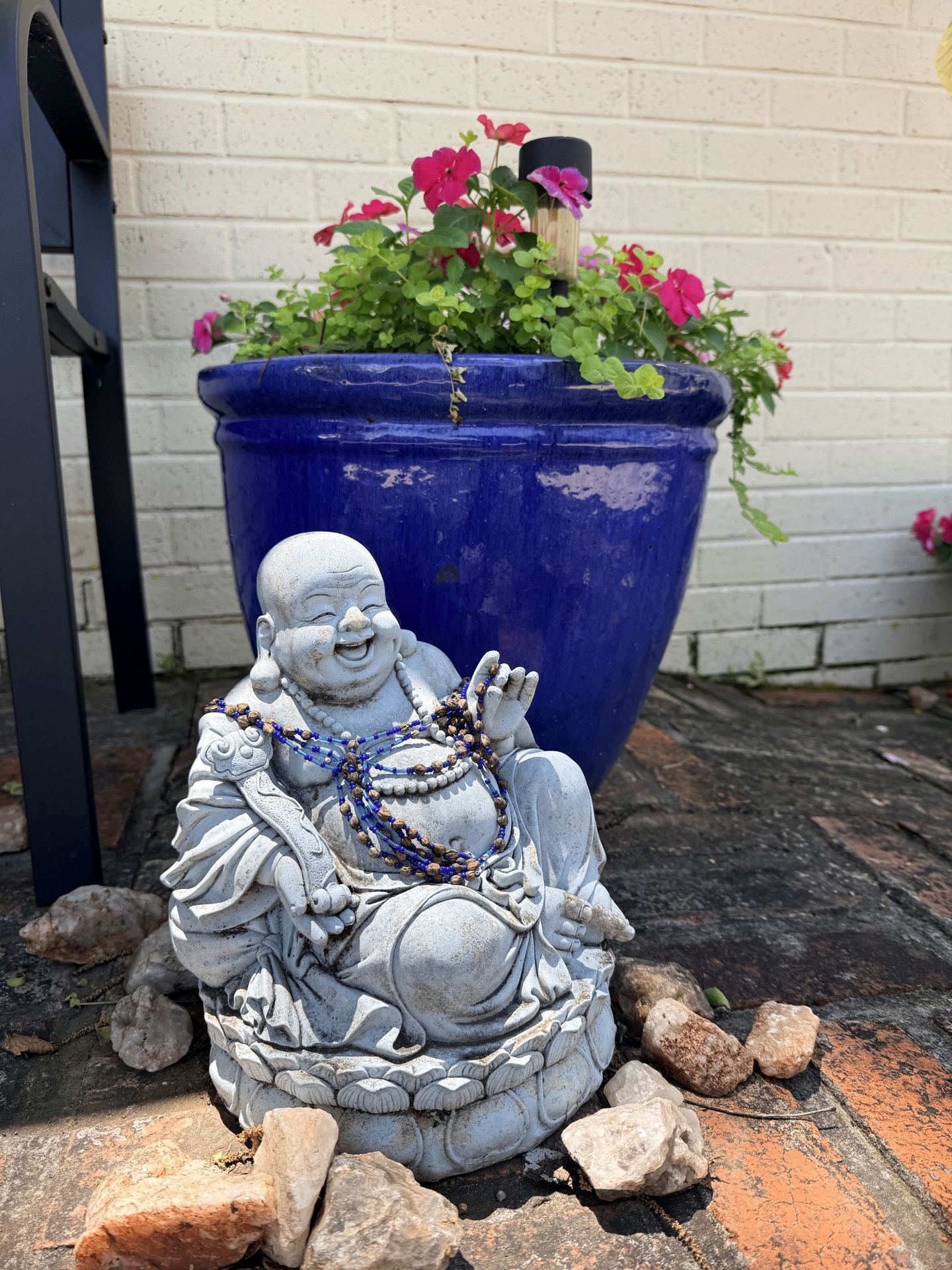 Laughing Buddha statue beside a blue planter at Blue Anjou Yoga Studio