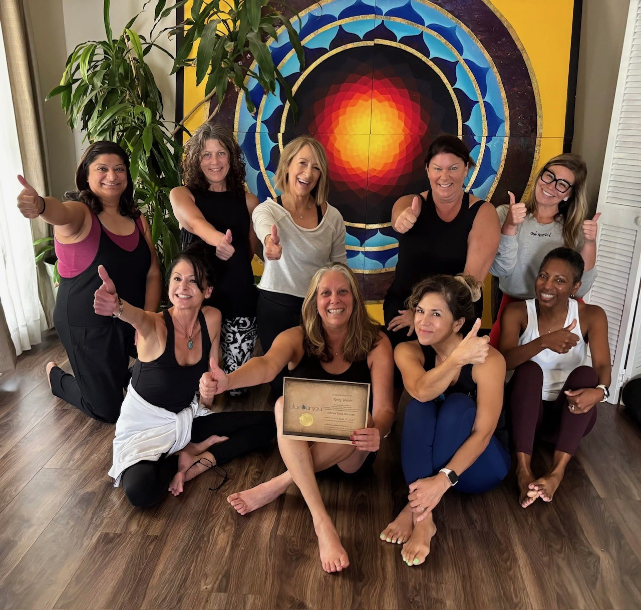 Blue Anjou teacher training graduates celebrating together at the studio