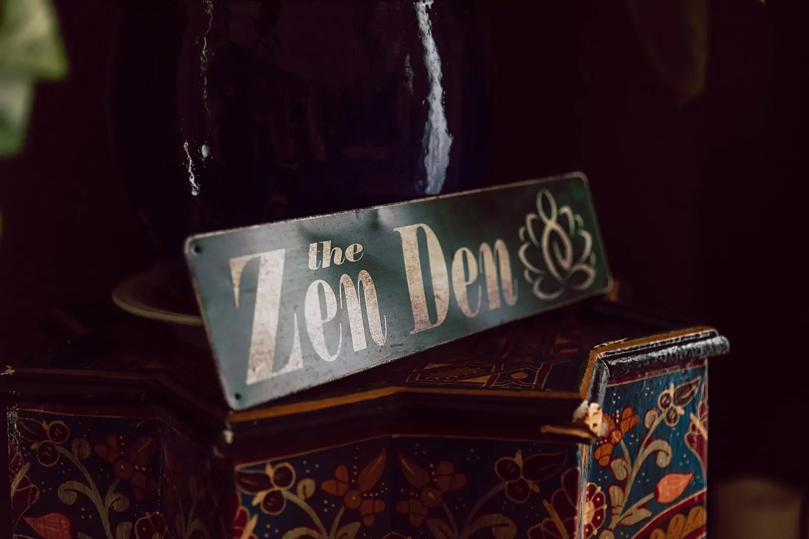 Hand-painted Zen Den sign resting on a painted wooden box