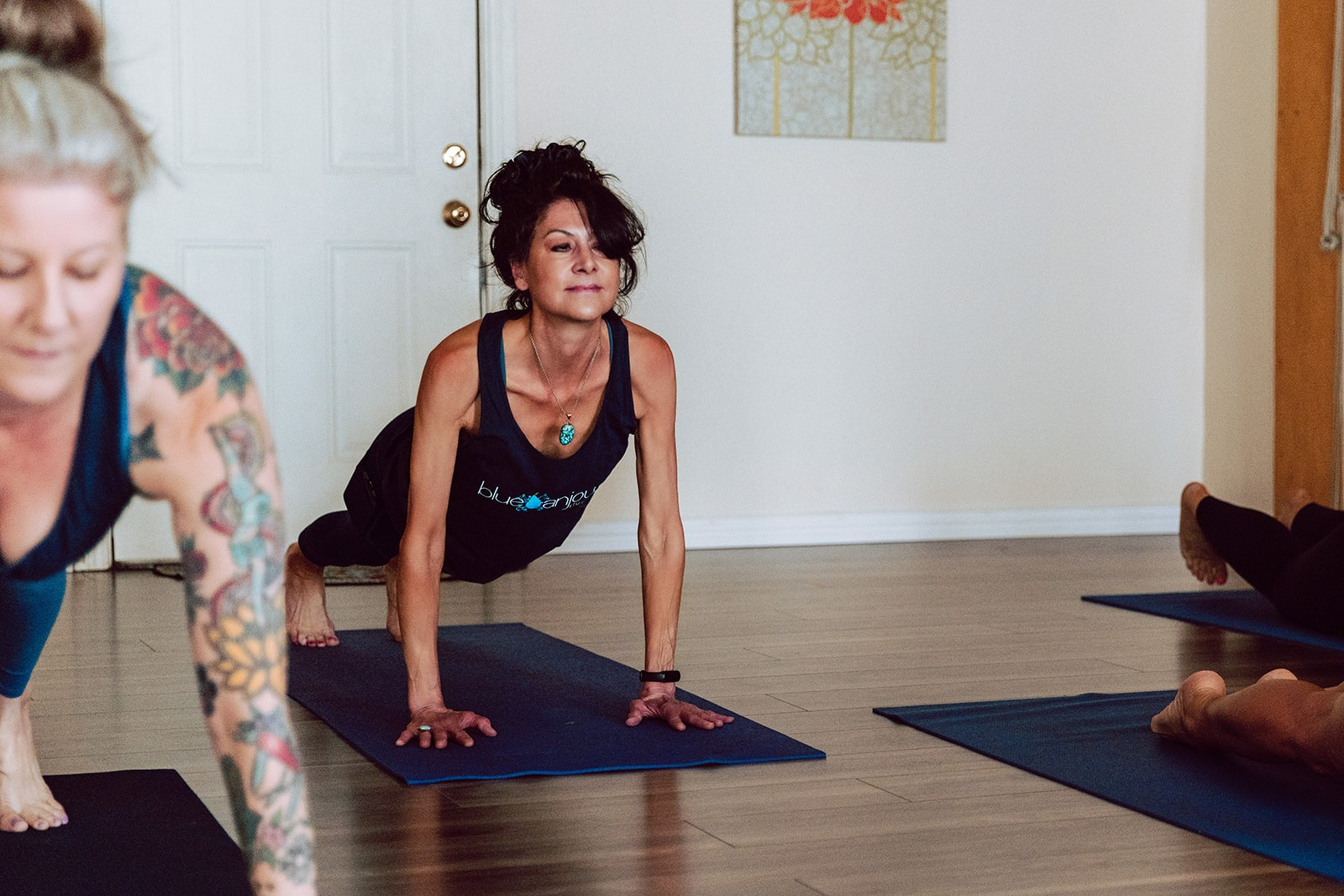Teacher guiding students through a low lunge on blue mats