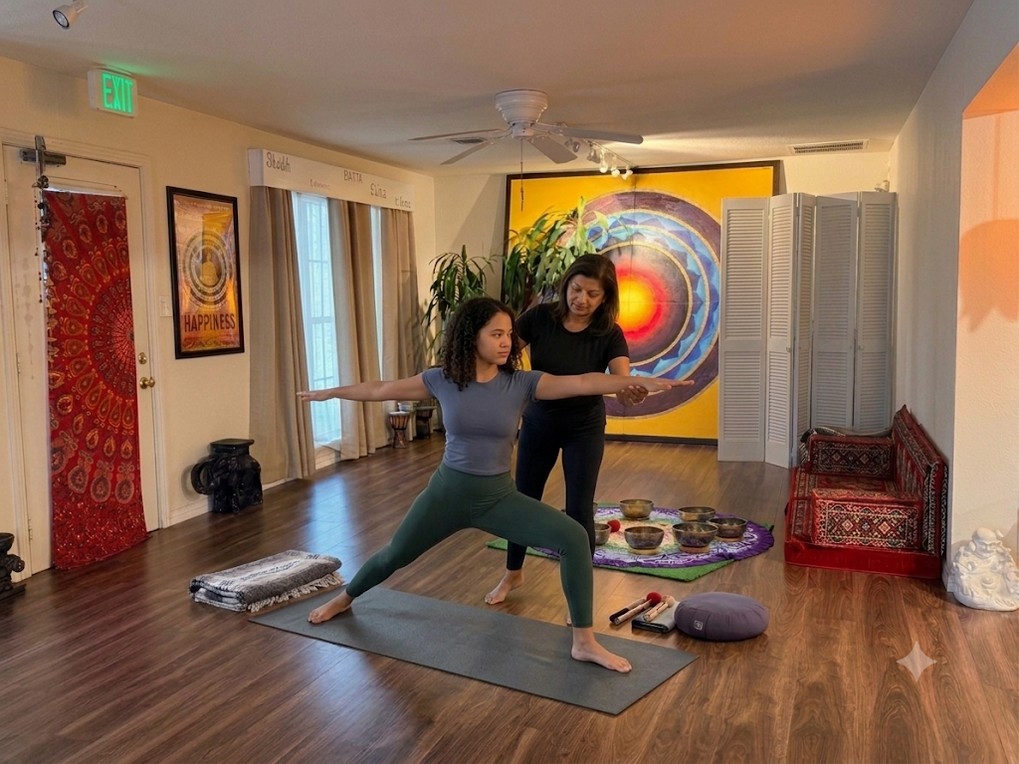 Blue Anjou teacher assisting a student in warrior II pose during a private yoga session