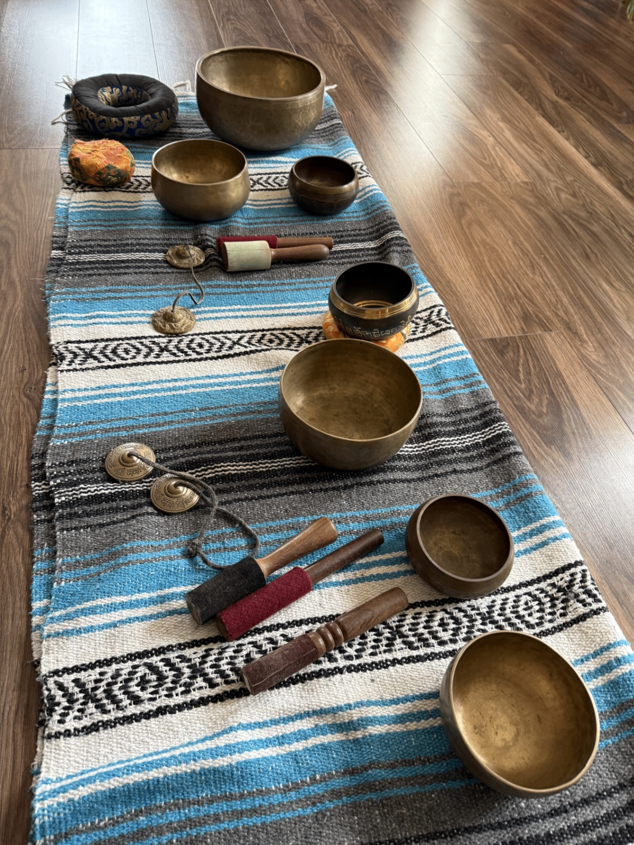 Sound healing bowls and instruments arranged on a woven blanket at Blue Anjou