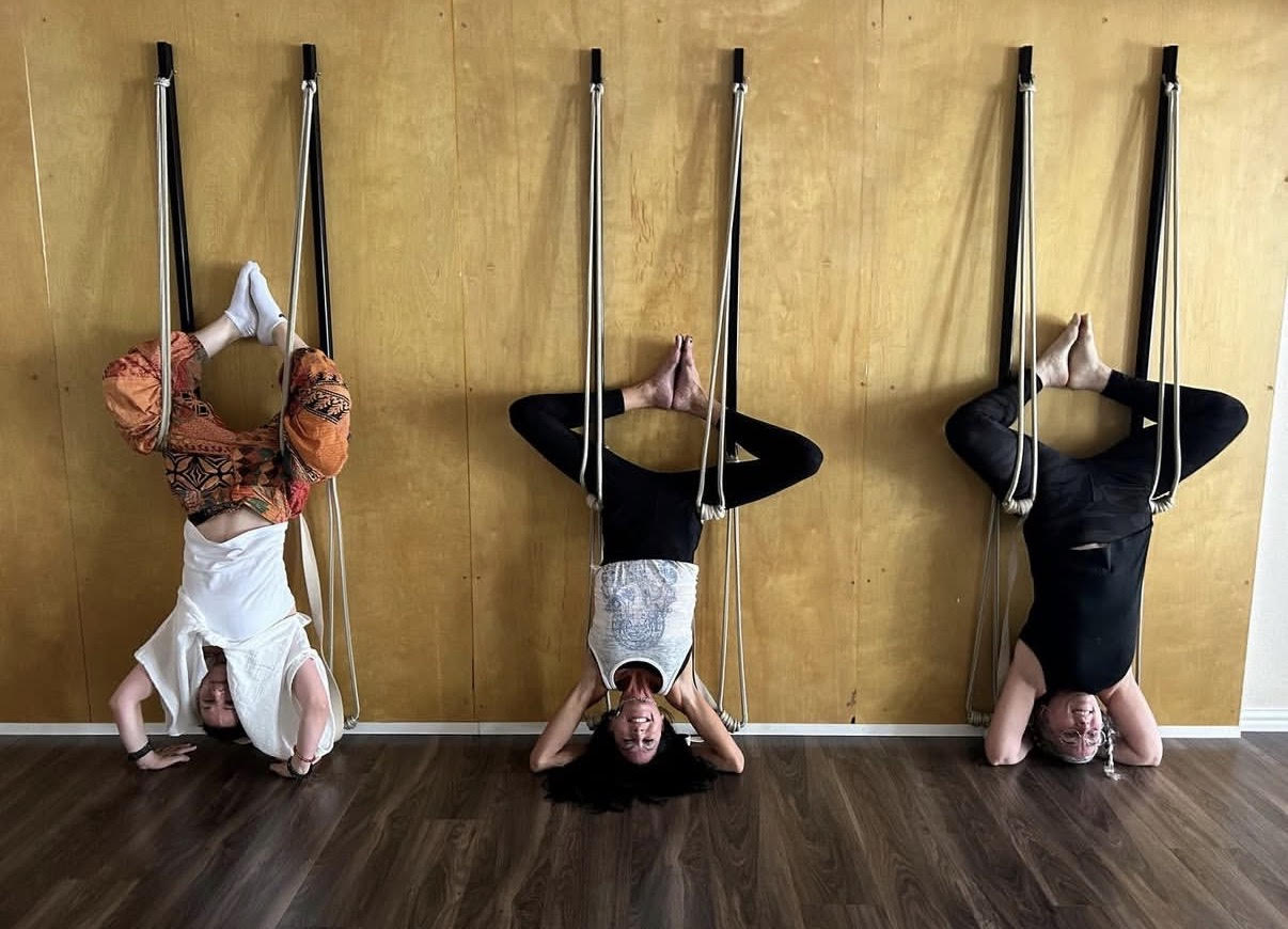 Three students practicing inversions on the Blue Anjou rope wall