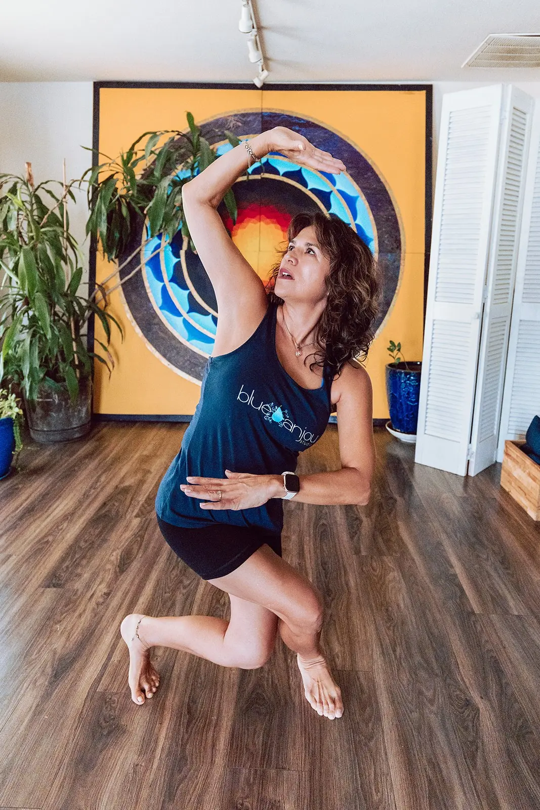 Teacher in a seated twist in front of the mandala painting